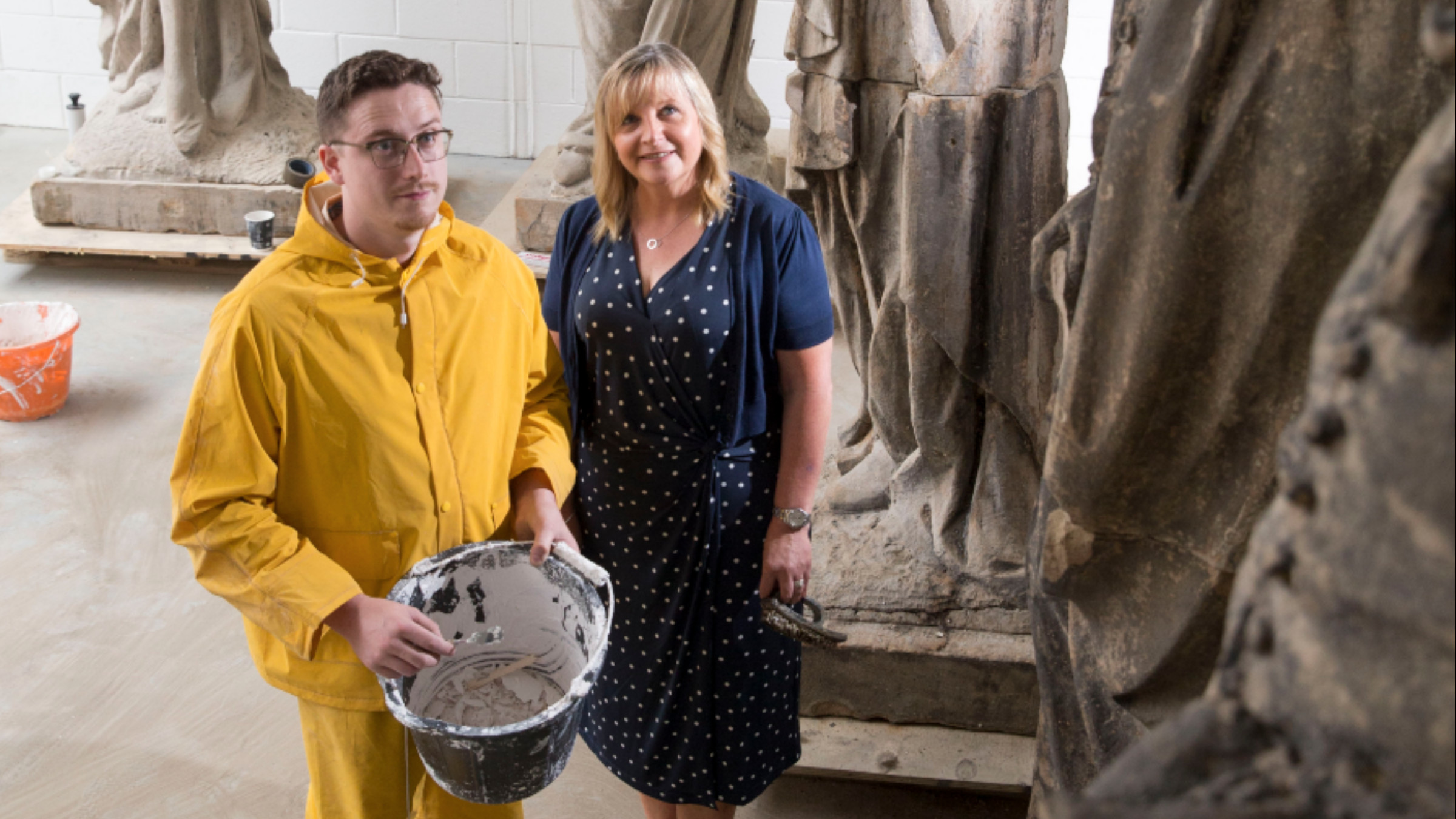 Sculptor David Mitchell wearing yellow overalls in Grovewood Business Centre studio with Jackie Taylor UKSE