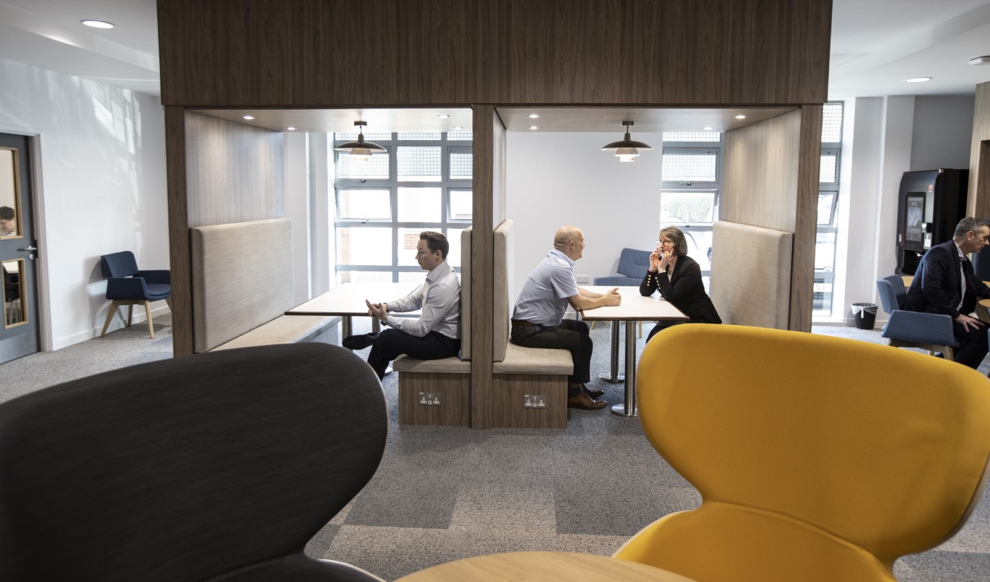People sitting and talking within a seating area with tables, chairs and booths inside UKSE's Kirkleatham Innovation Centre